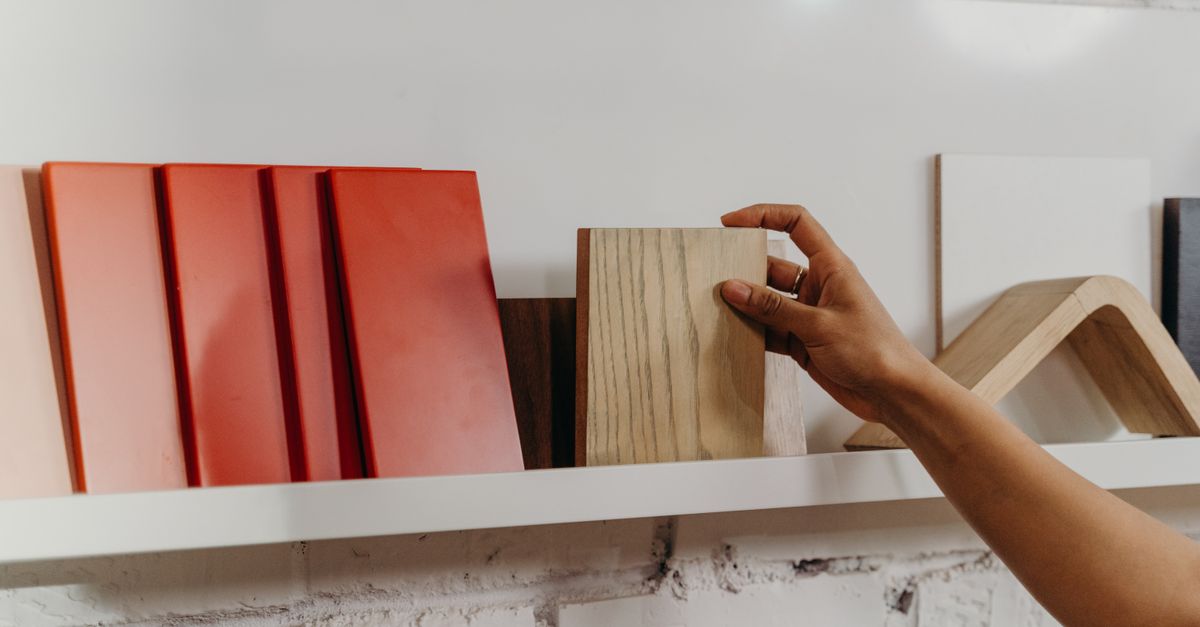 Mano che sceglie un campione di legno da una mensola espositiva