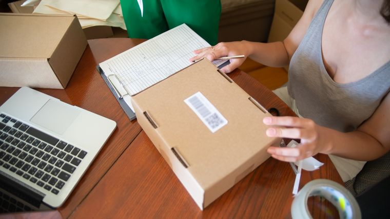 Due persone che preparano gli ordini di un piccolo negozio online, con gli scatoloni sul tavolo