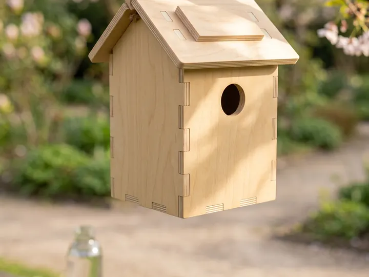 Casetta per uccelli in legno appesa a un ramo (immagine generata con AI)